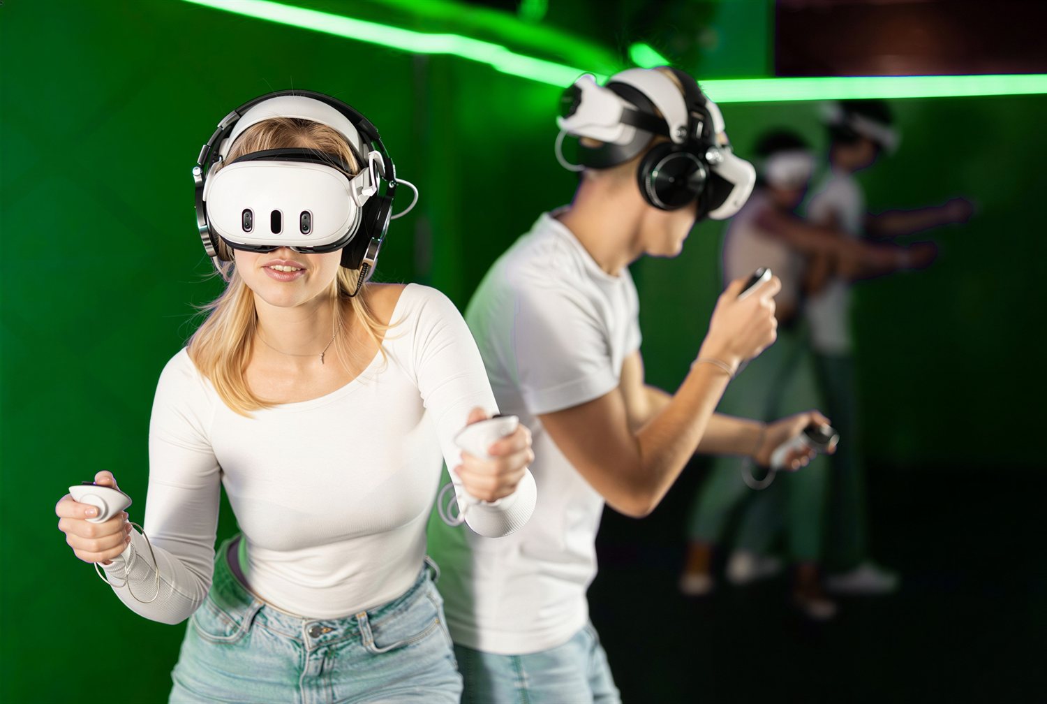 Four friends in VR headsets playing together in a green-lit event space